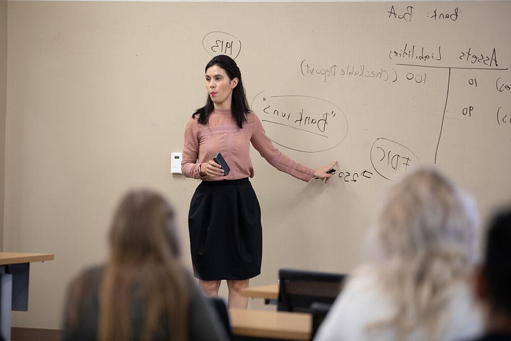 业务 professor teaches in front of a white board